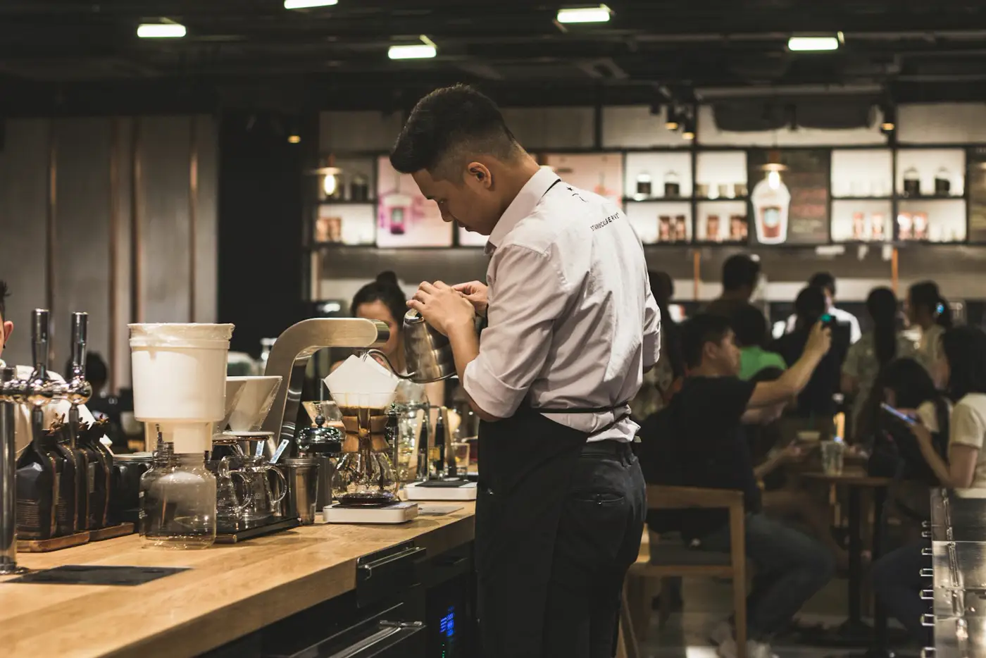 Barista preparando bebidas detrás de la barra del café